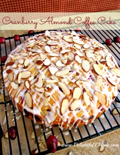 a cake sitting on top of a cooling rack covered in almonds and drizzled with icing