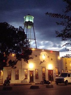 an old building with a water tower in the background at night, lit up by lights