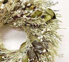 a wreath with white flowers and greenery is displayed on a wall or table top