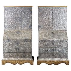 a pair of silver and gold dressers sitting side by side on top of each other