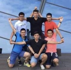 six young men posing for a photo on the deck of a boat with their arms in the air