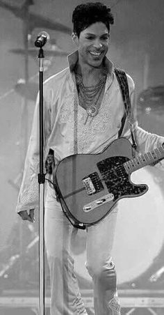 a man holding a guitar while standing in front of a microphone