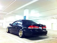 a black car is parked in a parking garage with yellow rims and gold wheels