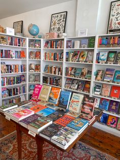 a room filled with lots of books on top of a wooden table next to a book shelf