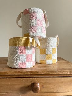 three quilted baskets sitting on top of a wooden table next to a drawer and knob