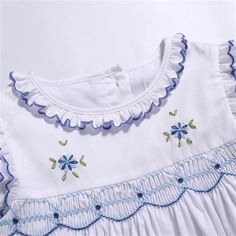 a white dress with blue trim and flowers on it