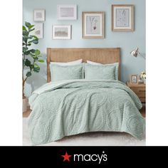 a bed in a bedroom with blue walls and pictures on the wall above it that says macy's