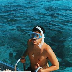 a man with goggles and snorkels standing on a boat in the water