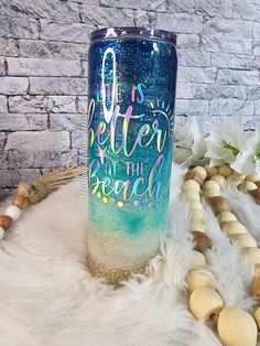 a blue and green glitter tumbler with the words better at the beach on it