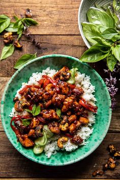 a green plate topped with chicken and rice on top of a wooden table next to flowers