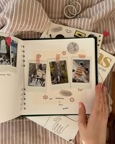 a person holding an open book on top of a bed covered in pictures and writing