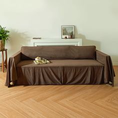 a living room with a brown couch and wooden floors in front of a white wall