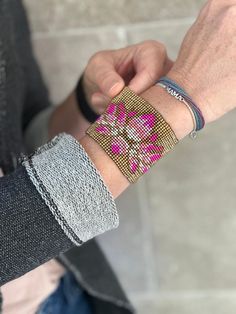 a person wearing two bracelets on their wrist and one has a pink flower in the middle