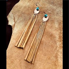 two pairs of earrings with long tassels on top of a piece of leather