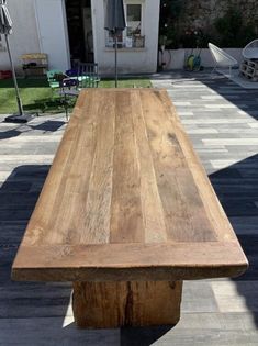 a large wooden table sitting on top of a tiled floor next to a white building