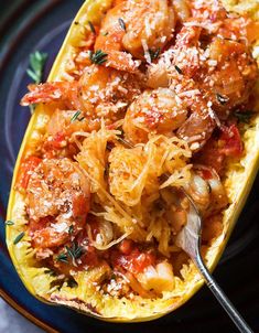 spaghetti dish with shrimp and tomato sauce in a squash boat on a blue plate, garnished with parmesan cheese