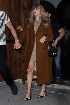 a man and woman holding hands while walking down the street