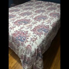 a bed with a white and red bedspread on top of wooden flooring