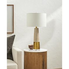 a lamp that is sitting on top of a wooden table next to a white chair