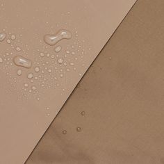 water drops on the side of a tan sheet with brown material in the foreground