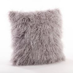 a gray furry pillow sitting on top of a white table