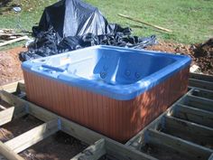 a hot tub sitting on top of pallets next to a yard with trash in the background