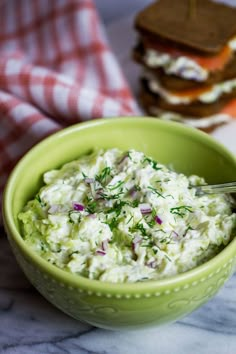 a green bowl filled with cucumber next to two slices of toasted bread