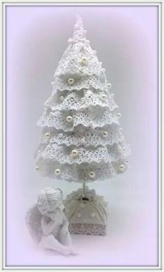 a white crocheted christmas tree next to a figurine