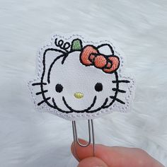 a hello kitty paper clip with a bow on it's head is held up by a hand