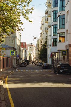 cars are parked on the side of an empty street in front of tall buildings with balconies