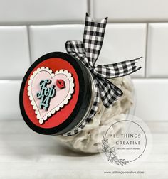 a jar filled with lots of white and red stuff on top of a counter next to a tile wall