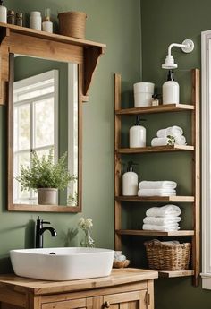 a bathroom sink sitting under a mirror next to a wooden shelf filled with white towels