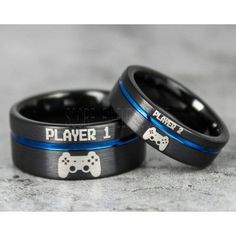 two black and blue wedding rings with video game controllers on each ring, sitting on a marble surface