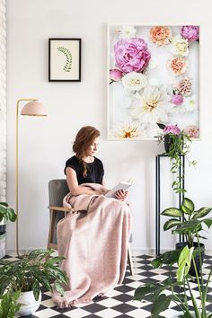 a woman sitting in a chair with a blanket on her lap looking at a magazine