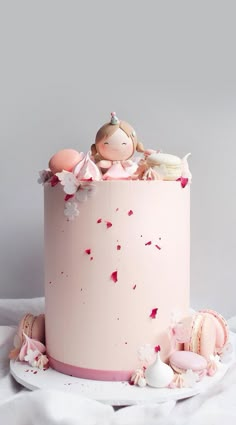 there is a pink cake decorated with figurines on the top, and frosting sprinkles all around it