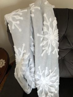 a blanket with white snowflakes on it sitting on a chair next to a table