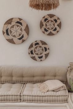 three woven plates hanging on the wall above a couch