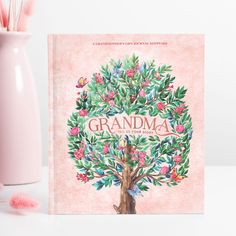 a pink vase and book cover with an illustration of a tree in the center, surrounded by flowers