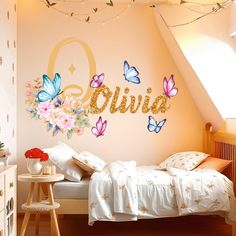 a bedroom decorated in pink and blue butterflies with gold glitter name decals on the wall