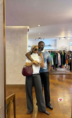 a man and woman taking a selfie in a clothing store