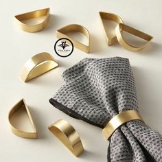 gold napkin rings and napkin holders on a white surface with a black tie laying next to them