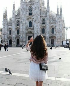 a woman standing in front of a cathedral taking a photo