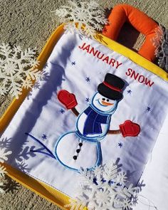 a snowman is on the ground next to an orange and white blanket with words january snow