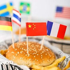 a burger with french fries and flags on it sitting in a basket next to other foods