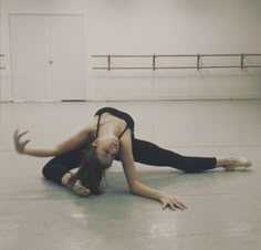 a woman in black shirt doing a handstand on the floor