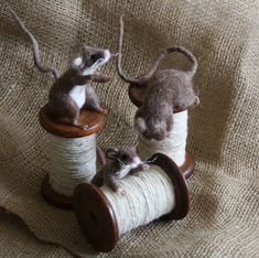 two small mice sitting on top of spools of thread