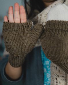 a woman holding her hands up to show the mittens on her left hand