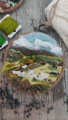 some yarns are sitting on a wooden table and there is a plate that has been painted