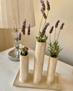 three vases with plants in them sitting on a white table next to a lamp