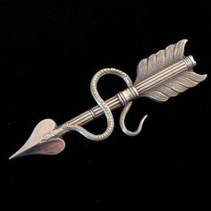 an arrow shaped brooch with a long tail and two feathers on it's end